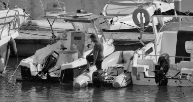 İtalya, Sicilya, Akdeniz, Marina di Ragusa (Ragusa Eyaleti); 1 Ekim 2025, limanda bir kauçuk teknede adam - EDITORIAL