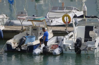 İtalya, Sicilya, Akdeniz, Marina di Ragusa (Ragusa Eyaleti); 1 Ekim 2025, limanda bir kauçuk teknede adam - EDITORIAL