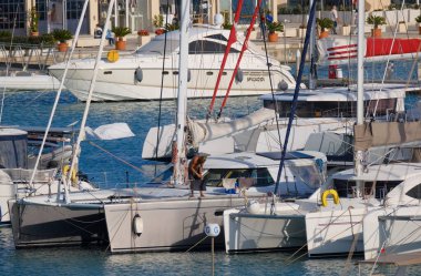 İtalya, Sicilya, Akdeniz, Marina di Ragusa (Ragusa Eyaleti); 4 Ekim 2025, limandaki bir katamaran yelkenli teknesinde adam - EDITORIAL