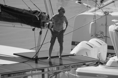 İtalya, Sicilya, Akdeniz, Marina di Ragusa (Ragusa Eyaleti); 5 Ekim 2025, limandaki bir katamaran yelkenli teknesinde adam - EDITORIAL