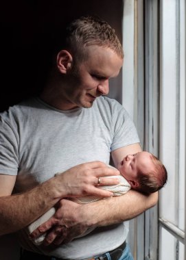 Kollarında küçük tatlı bir kız çocuğu olan genç bir babanın görüntüsü. Baba ve yeni doğan bebek.