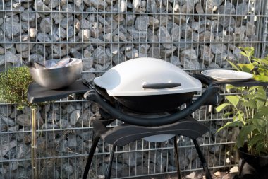 Metal bir kasede ızgara için hazırlanmış taze balıkla modern bir açık hava ızgarası. Dekoratif bir kaya duvarına kurulmuş, sıradan, kaba bir ortam yaratıyor..