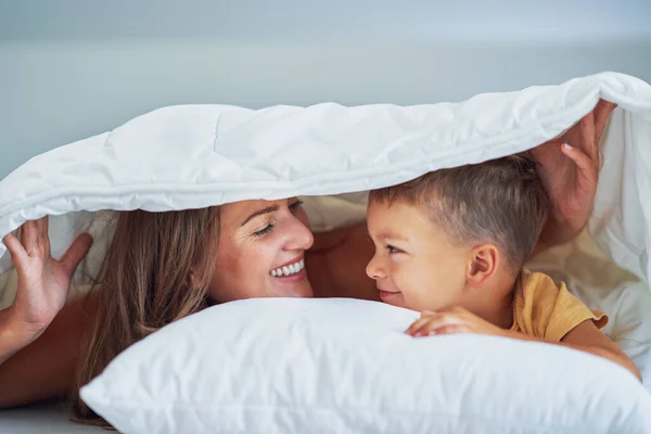 Young mother with 4 years old son in bed. High quality photo