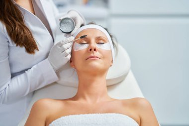 Woman having cosmetology eyebrows treatment in beauty salon. High quality photo