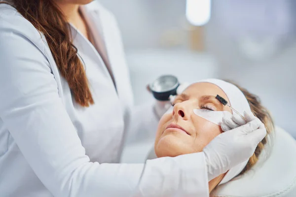 Woman having cosmetology eyebrows treatment in beauty salon. High quality photo