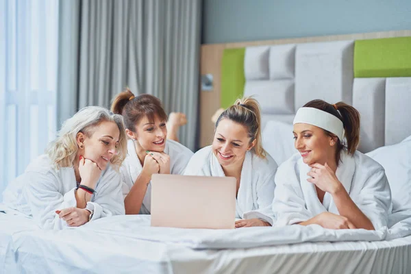 Group of girl friends at hotel spa party with laptop. High quality photo