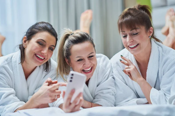 Girls at spa party in hotel with phone. High quality photo
