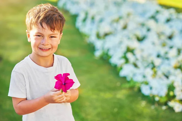 Φωτογραφία Ενός Νεαρού Αγοριού Χαμογελάει Ένα Λουλούδι Στο Χέρι Υψηλής — Φωτογραφία Αρχείου