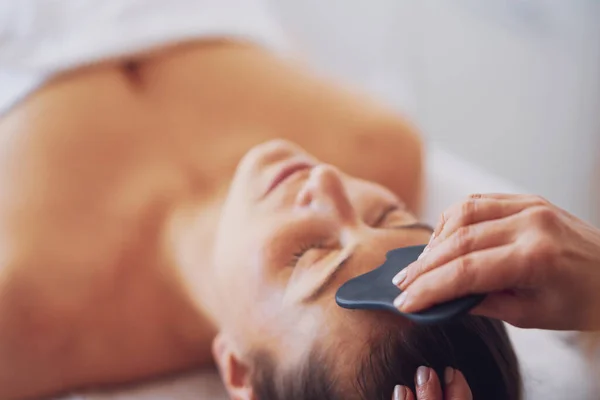 Brunette Vrouw Met Een Stenen Massage Haar Gezicht Hoge Kwaliteit — Stockfoto
