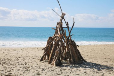 Beach Hut. A small structure built out of driftwood tree branches on the beach. Shelter from the storm. Drift Wood House