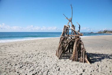 Beach Hut. A small structure built out of driftwood tree branches on the beach. Shelter from the storm. Drift Wood House