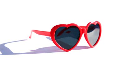 Beyaz arkaplanda kalp şeklinde kırmızı güneş gözlüğü