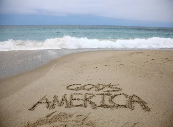 ビーチで砂の中に書かれた神のアメリカの笑顔 滑らかな砂浜に手書きのメッセージ — ストック写真