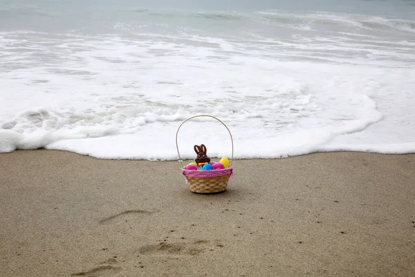 Easter Basket in the sand by the ocean. A Easter Basket with   a Chocolate Bunny, Plastic Eggs  on the beach by the ocean. Happy Easter to all
