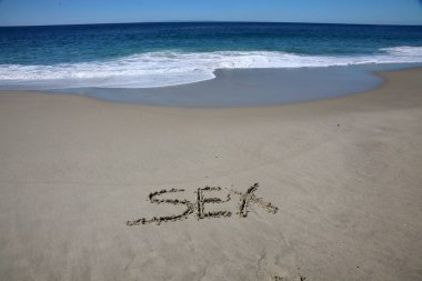 sex written in the sand on the beach.  message handwritten on a smooth sand beach