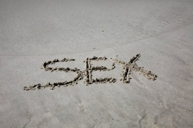 sex written in the sand on the beach.  message handwritten on a smooth sand beach
