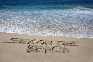 sex on the beach written in the sand on the beach.  message handwritten on a smooth sand beach 