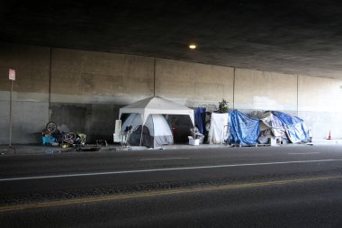Long Beach, California - ABD - 16 Nisan 2023: Trafik şeridinde bir duvara karşı evsiz barınağı. Evsizlik toplum ve yoksulluktan etkilenen insanlar için ulusal bir sorun haline geldi..