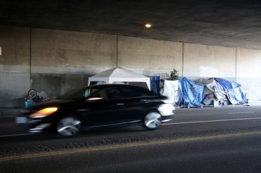 Long Beach, California - ABD - 16 Nisan 2023: Trafik şeridinde bir duvara karşı evsiz barınağı. Evsizlik toplum ve yoksulluktan etkilenen insanlar için ulusal bir sorun haline geldi..