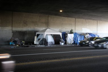 Long Beach, California - ABD - 16 Nisan 2023: Trafik şeridinde bir duvara karşı evsiz barınağı. Evsizlik toplum ve yoksulluktan etkilenen insanlar için ulusal bir sorun haline geldi..
