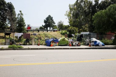 Long Beach, California - ABD - 16 Nisan 2023: Trafik şeridinde bir duvara karşı evsiz barınağı. Evsizlik toplum ve yoksulluktan etkilenen insanlar için ulusal bir sorun haline geldi..