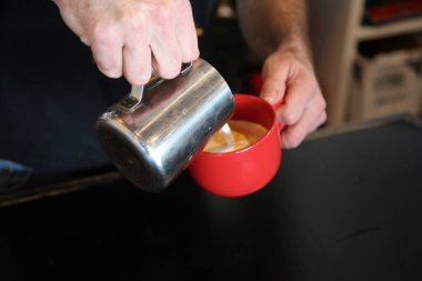 Sütlü. Kahve fincanı latte sanatı. Kapuçino ya da köpüklü latte, kırmızı kahve fincanı. Üst görünüm yakın plan. 