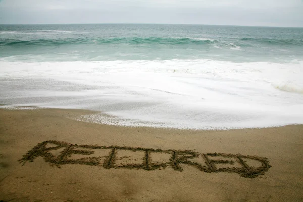 海を背景にビーチサンドで書かれた退職 — ストック写真