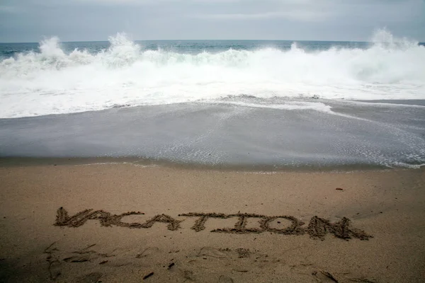海を背景にビーチサンドで書かれた休暇 — ストック写真