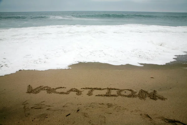 海を背景にビーチサンドで書かれた休暇 — ストック写真