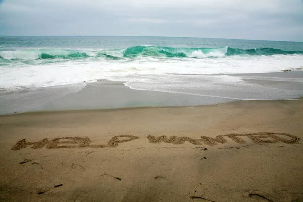 Pomoc Chciał Napisany Piasku Plaży Oceanem Jako Tło — Zdjęcie stockowe