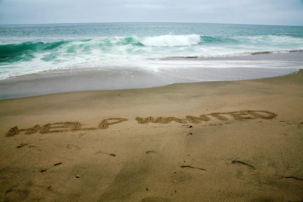 Помощь Хотел Написан Пляже Песок Океаном Качестве Фона — стоковое фото
