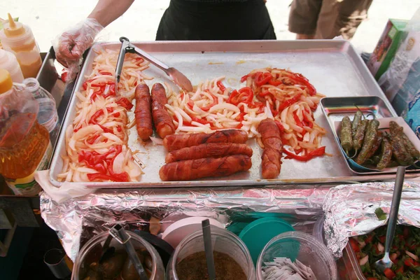 Food. Bacon Wrapped Hot Dogs. Grilled Onions and Peppers. Hot Dog Cart. Food Cart. Hot Dogs being cooked and offered for sale on the side walk of Hollywood California. Hungry Tourist enjoy Hot Dogs.