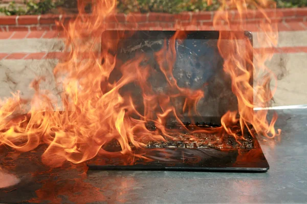 ノートパソコンやキーボードの燃焼 機器の故障によるバッテリーや配線の火災 炎の中でノートパソコンが燃える 火災危険 — ストック写真