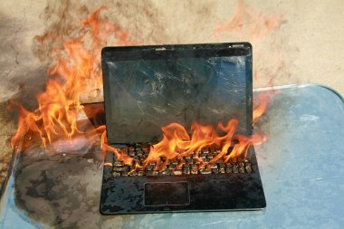 Burning laptop and keyboard. Laptop Computer on fire. Laptop burning in flames. Fire hazard. Losing valuable data. Computer Damage. Haunted laptop. Fire due to Evil. Computer in Hell. Halloween. clipart