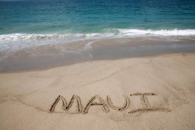 Pasifik Okyanusu 'nun arka planında kumlara yazılmış Maui ismi.. 