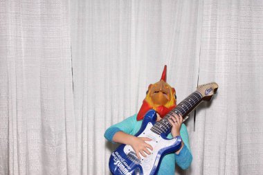 Penis kafalı bir adam fotoğraf kabininde resimlerinin çekilmesini beklerken gitarla poz verir..