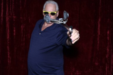 Güneş gözlüklü gülümseyen bir adam bir partide fotoğraf kabininde fotoğraf çektirmek için poz veriyor.. 