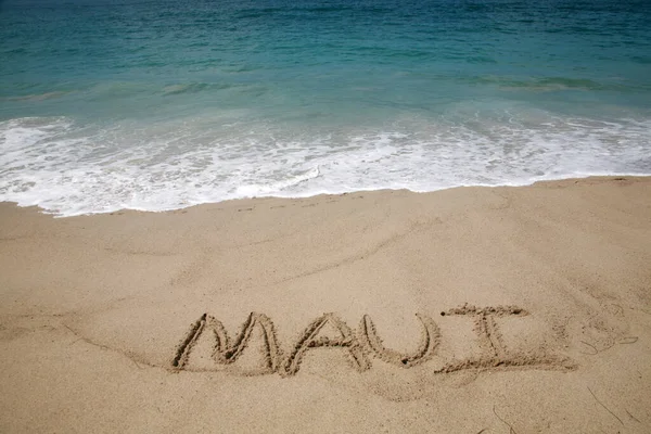 パシフィック オーシャン バックグラウンドのビーチで砂で書かれたマウイの名前 — ストック写真