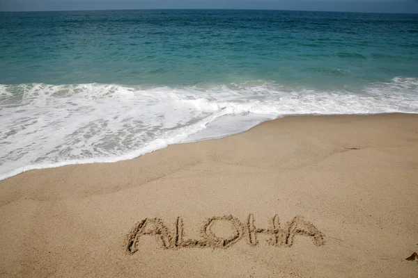 The word ALOHA written in the sand on the beach in Hawaii.