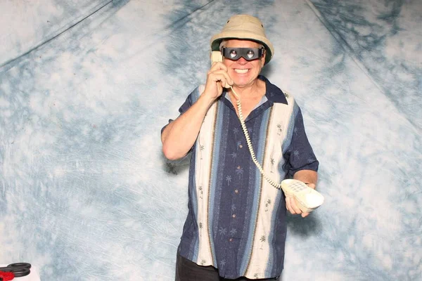 A man listens to a Sales Pitch on his Old School Wired Telephone while having his picture taken in a Photo Booth