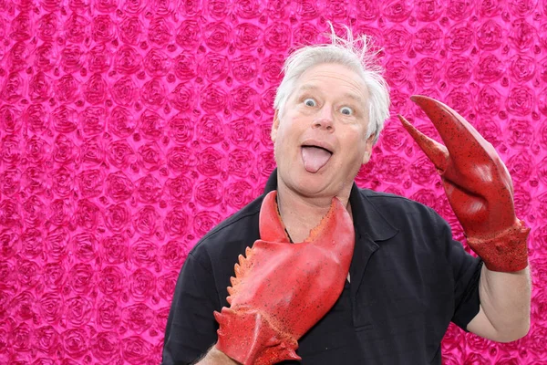 Photo Booth. A man makes a funny face and poses for his picture to be taken while he is attacked by LOBSTER CLAW HANDS while in a Photo Booth at a party.