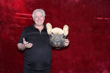 Bir adam köpek maskesi takar ve fotoğraflarının çekilmesi için bir düğünde veya partide fotoğraf kabininde poz verir.. 