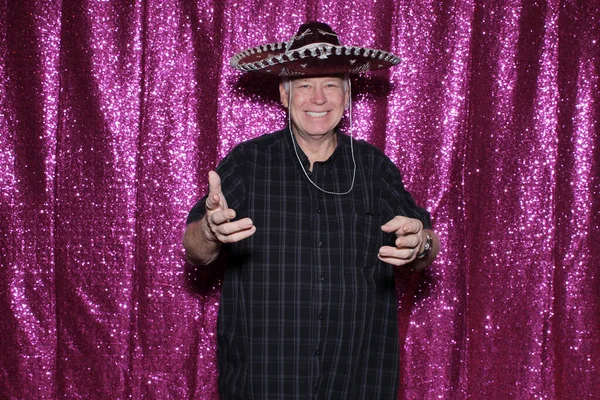 Photo Booth. A man wears a Sombrero and smiles as he waits for his pictures to be taken while enjoying a Photo Booth at a Wedding or Party. People love Photo Booths and get pictures printed instantly.