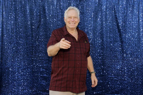 A man Smiles and points at camera for his pictures to be taken while in a Photo Booth at a Wedding or Party.