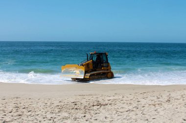 Kaliforniya, Laguna Sahili 'ndeki kumu bir buldozer temizliyor. Buldozerler kum patlamalarını taşımak ve insanların yaralanabileceği yerleri doldurmak için kullanılır.. 
