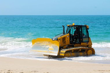 Kaliforniya, Laguna Sahili 'ndeki kumu bir buldozer temizliyor. Buldozerler kum patlamalarını taşımak ve insanların yaralanabileceği yerleri doldurmak için kullanılır.. 