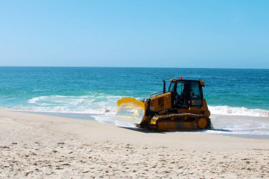 Kaliforniya, Laguna Sahili 'ndeki kumu bir buldozer temizliyor. Buldozerler kum patlamalarını taşımak ve insanların yaralanabileceği yerleri doldurmak için kullanılır.. 
