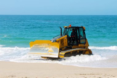 Kaliforniya, Laguna Sahili 'ndeki kumu bir buldozer temizliyor. Buldozerler kum patlamalarını taşımak ve insanların yaralanabileceği yerleri doldurmak için kullanılır.. 