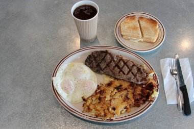 Biftek ve yumurta kahvaltısı. Biftekli kahvaltı, 3 yumurta, haşhaşlı patates, tereyağlı ekşi ekmek ve kremalı kahve. Yiyecek ve içecek. Yiyecekler. Kahvaltıda. Yumurtalar. Biftek. - Kahve. - Şerefe. Esrar Browns. Bıçak. Çatal. Kaşık. Tabak. - Öğle yemeği. Akşam yemeği. Atıştırmalık. 