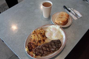 Biftek ve yumurta kahvaltısı. Biftekli kahvaltı, 3 yumurta, haşhaşlı patates, tereyağlı ekşi ekmek ve kremalı kahve. Yiyecek ve içecek. Yiyecekler. Kahvaltıda. Yumurtalar. Biftek. - Kahve. - Şerefe. Esrar Browns. Bıçak. Çatal. Kaşık. Tabak. - Öğle yemeği. Akşam yemeği. Atıştırmalık. 
